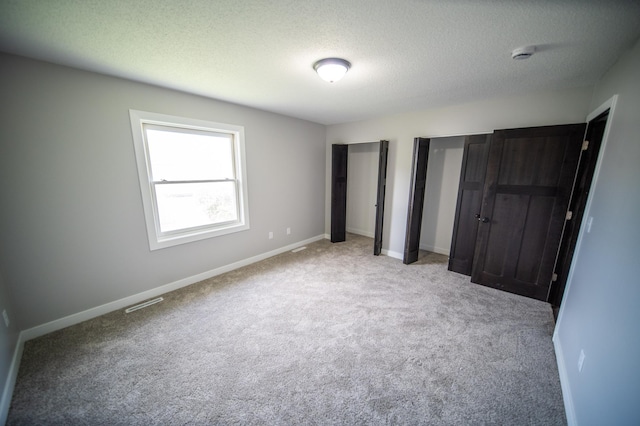 4703 7th St NW, Rochester, MN 55901 - unfurnished bedroom featuring carpet, two closets, a textured ceiling, and baseboards