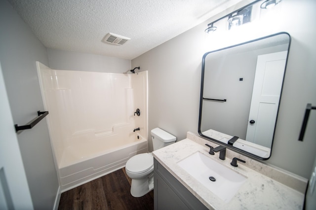 4703 7th St NW, Rochester, MN 55901 - full bathroom featuring toilet, wood finished floors, vanity, washtub / shower combination, and a textured ceiling