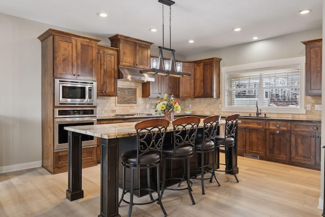15653 Cobblestone Lake Pkwy, Apple Valley, MN 55124 - kitchen featuring appliances with stainless steel finishes, recessed lighting, backsplash, a breakfast bar, and light wood-type flooring