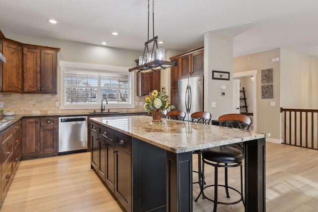 15653 Cobblestone Lake Pkwy, Apple Valley, MN 55124 - kitchen with appliances with stainless steel finishes, a sink, a kitchen bar, a center island, and light wood finished floors