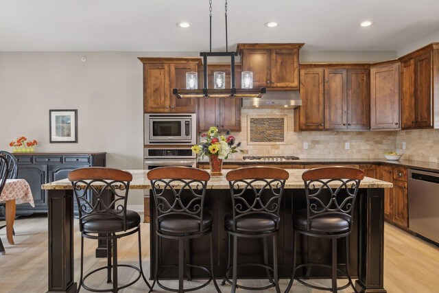 15653 Cobblestone Lake Pkwy, Apple Valley, MN 55124 - kitchen with appliances with stainless steel finishes, under cabinet range hood, a kitchen island with sink, decorative backsplash, and recessed lighting