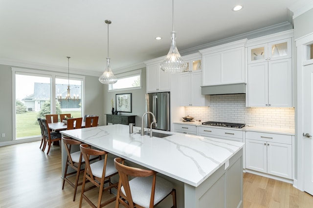 2720 Bentley Dr SW, Rochester, MN 55902 - kitchen featuring appliances with stainless steel finishes, a sink, light wood-type flooring, ornamental molding, and a center island with sink