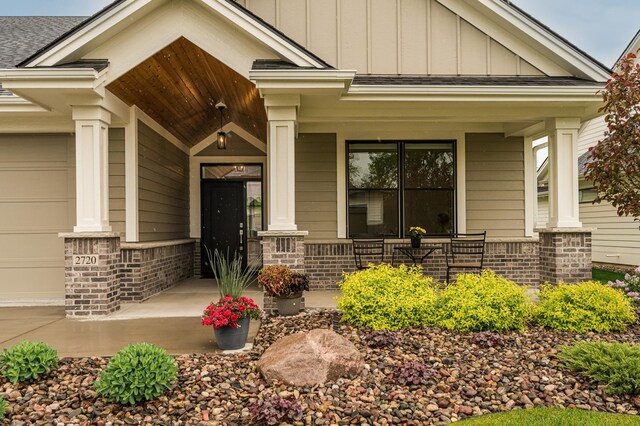 2720 Bentley Dr SW, Rochester, MN 55902 - doorway to property featuring a porch, board and batten siding, a garage, and a shingled roof