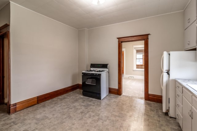 2320 3rd St N, Saint Cloud, MN 56303 - kitchen featuring gas range oven, freestanding refrigerator, white cabinets, baseboards, and light countertops