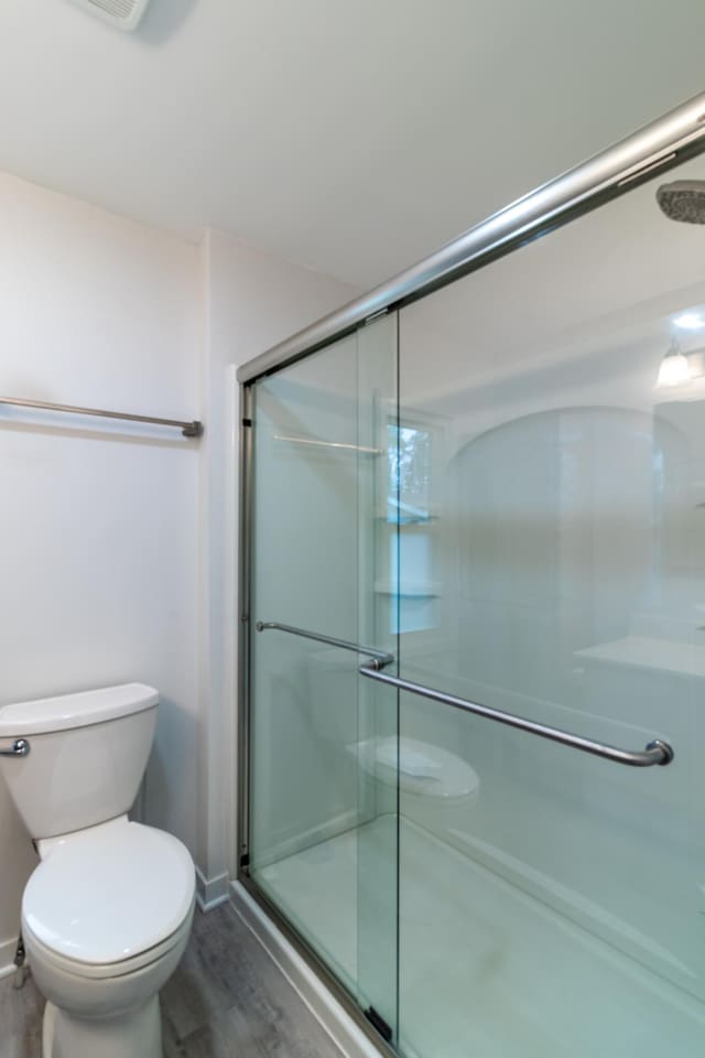 2320 3rd St N, Saint Cloud, MN 56303 - bathroom with a stall shower, toilet, wood finished floors, and baseboards