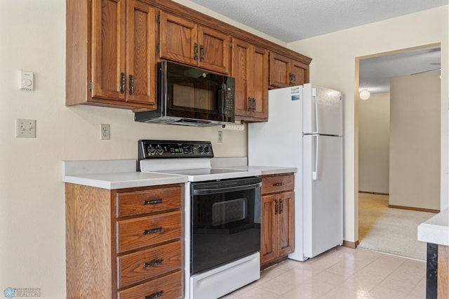 2802 29th Ave S, Moorhead, MN 56560 - kitchen featuring electric range oven, black microwave, light countertops, brown cabinets, and freestanding refrigerator