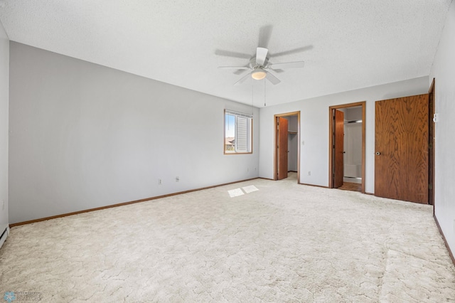 2802 29th Ave S, Moorhead, MN 56560 - unfurnished bedroom with carpet flooring, a textured ceiling, a walk in closet, baseboards, and ceiling fan