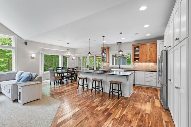 8580 Maple View Dr, Cologne, MN 55322 - kitchen featuring a kitchen breakfast bar, stainless steel appliances, open floor plan, decorative backsplash, and glass insert cabinets