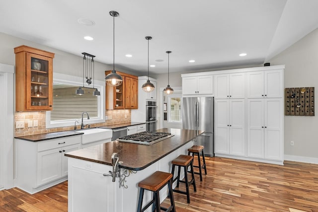 8580 Maple View Dr, Cologne, MN 55322 - kitchen with appliances with stainless steel finishes, a sink, dark countertops, a kitchen bar, and light wood-style flooring