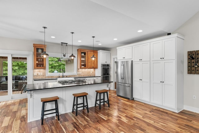 8580 Maple View Dr, Cologne, MN 55322 - kitchen with appliances with stainless steel finishes, glass insert cabinets, decorative backsplash, dark countertops, and a kitchen breakfast bar