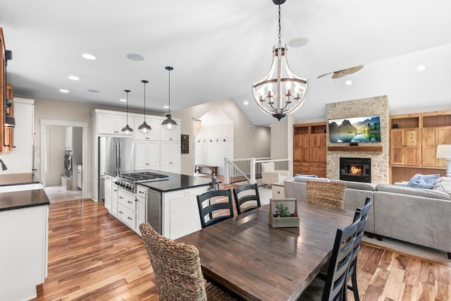 8580 Maple View Dr, Cologne, MN 55322 - dining room featuring light wood finished floors, recessed lighting, a stone fireplace, a chandelier, and vaulted ceiling