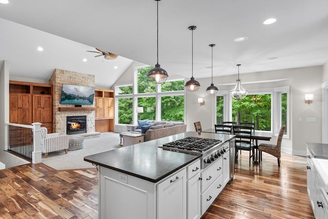 8580 Maple View Dr, Cologne, MN 55322 - kitchen featuring a ceiling fan, stainless steel gas cooktop, dark countertops, a stone fireplace, and hardwood / wood-style flooring