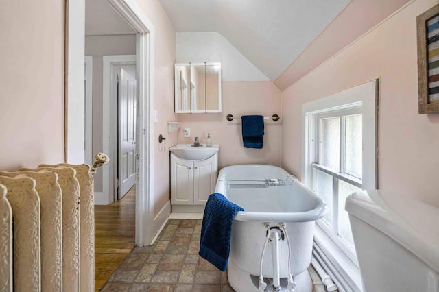 504 4th St, Brainerd, MN 56401 - full bathroom featuring a soaking tub, lofted ceiling, vanity, stone finish flooring, and baseboards