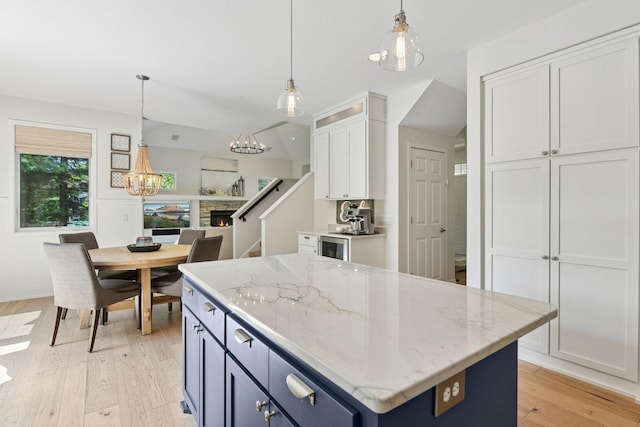 9375 Cold Stream Ln, Eden Prairie, MN 55347 - kitchen featuring white cabinetry, a chandelier, light wood-style floors, a center island, and hanging light fixtures