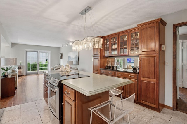 1511 Colleen Ave, Arden Hills, MN 55112 - kitchen with stainless steel electric stove, a chandelier, open floor plan, brown cabinets, and a kitchen island
