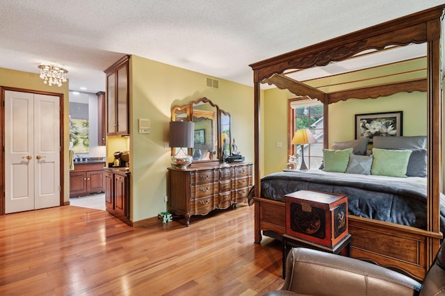 1511 Colleen Ave, Arden Hills, MN 55112 - bedroom with light wood-type flooring, a textured ceiling, ensuite bath, and a chandelier