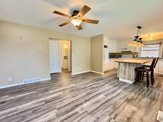 115 1st St SE, Pelican Rapids, MN 56572 - kitchen with white appliances, wooden counters, white cabinetry, a kitchen island, and wood finished floors