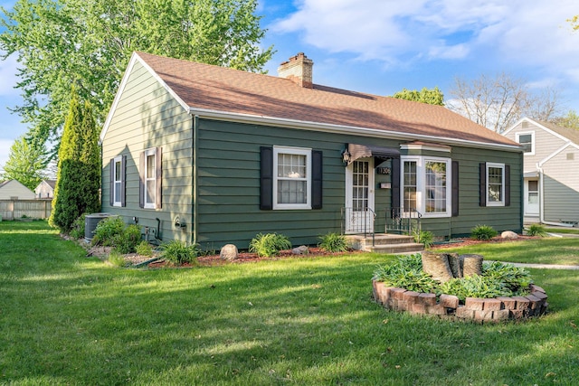 1306 3rd Ave SW, Austin, MN 55912 - view of front of house featuring a chimney, a front lawn, central AC, and roof with shingles