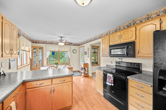 2101 Blake Ave, Lester Prairie, MN 55354 - kitchen with black appliances, a peninsula, light wood-type flooring, ceiling fan, and dark countertops