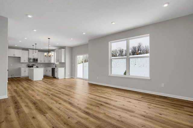 10664 29th St NE, Saint Michael, MN 55376 - unfurnished living room with a chandelier, recessed lighting, light wood finished floors, baseboards, and a sink