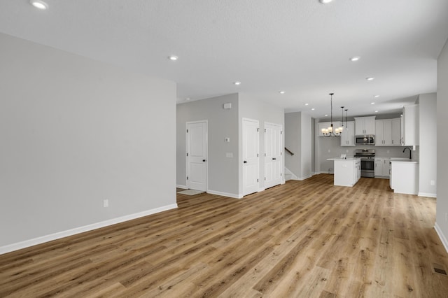 10664 29th St NE, Saint Michael, MN 55376 - unfurnished living room with a sink, recessed lighting, light wood-style flooring, baseboards, and stairs