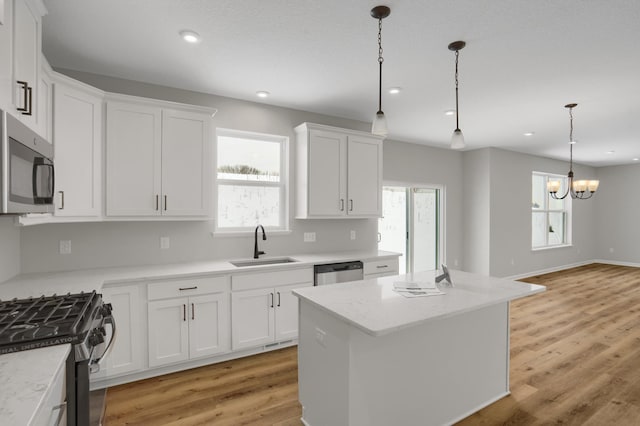 10664 29th St NE, Saint Michael, MN 55376 - kitchen featuring stainless steel appliances, a sink, white cabinetry, pendant lighting, and a chandelier
