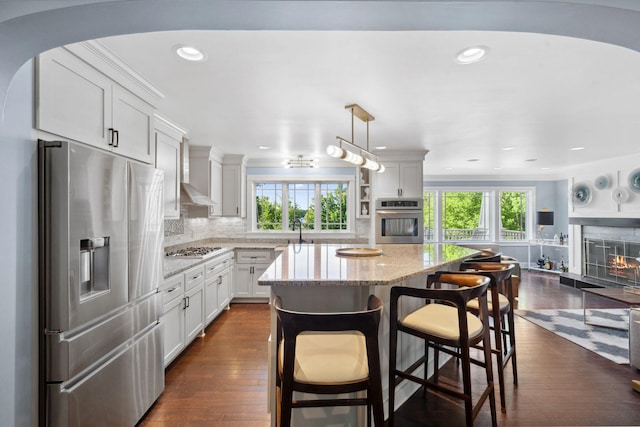 17209 Grays Bay Blvd, Minnetonka, MN 55391 - kitchen with appliances with stainless steel finishes, healthy amount of natural light, a glass covered fireplace, light stone counters, and recessed lighting
