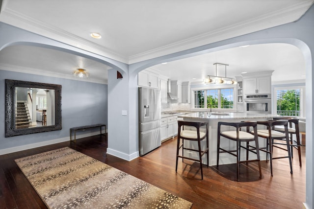 17209 Grays Bay Blvd, Minnetonka, MN 55391 - kitchen featuring appliances with stainless steel finishes, arched walkways, dark wood-style flooring, white cabinets, and crown molding