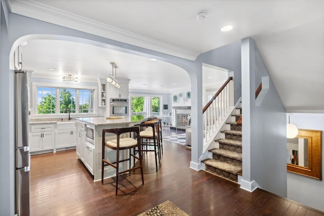 17209 Grays Bay Blvd, Minnetonka, MN 55391 - kitchen with arched walkways, a kitchen breakfast bar, stainless steel appliances, white cabinets, and light stone countertops