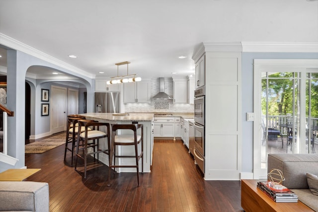 17209 Grays Bay Blvd, Minnetonka, MN 55391 - kitchen featuring wall chimney range hood, stainless steel appliances, a breakfast bar, tasteful backsplash, and light stone counters