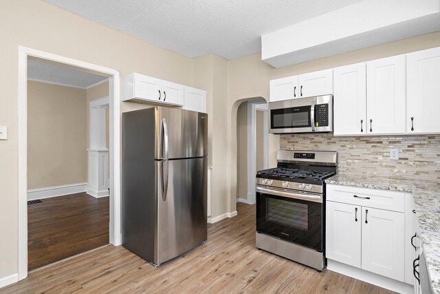 248 Ivy Ave W, Saint Paul, MN 55117 - kitchen featuring appliances with stainless steel finishes, arched walkways, light wood-style floors, white cabinetry, and a textured ceiling