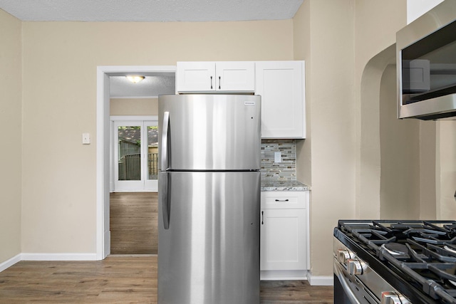 248 Ivy Ave W, Saint Paul, MN 55117 - kitchen featuring appliances with stainless steel finishes, decorative backsplash, light stone counters, and white cabinetry