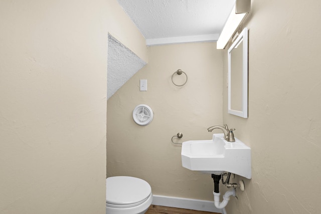 248 Ivy Ave W, Saint Paul, MN 55117 - half bath featuring a textured ceiling, toilet, wood finished floors, and baseboards