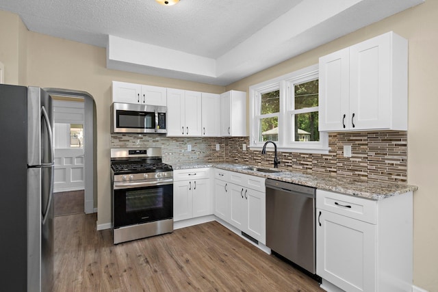 248 Ivy Ave W, Saint Paul, MN 55117 - kitchen featuring stainless steel appliances, a sink, wood finished floors, decorative backsplash, and a textured ceiling