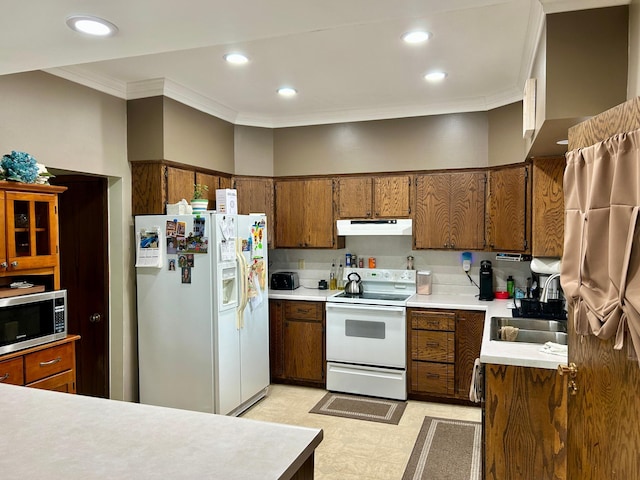 214 2nd St SW, Wadena, MN 56482 - kitchen featuring white appliances, a sink, under cabinet range hood, brown cabinets, and crown molding