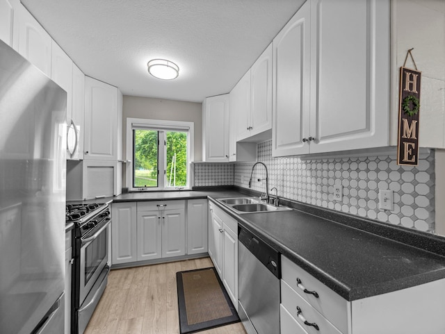 10720 Rockford Rd Unit 113, Plymouth, MN 55442 - kitchen with appliances with stainless steel finishes, a sink, light wood-type flooring, dark countertops, and white cabinetry
