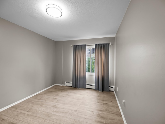 10720 Rockford Rd Unit 113, Plymouth, MN 55442 - unfurnished room with light wood finished floors, baseboards, a baseboard heating unit, and a textured ceiling