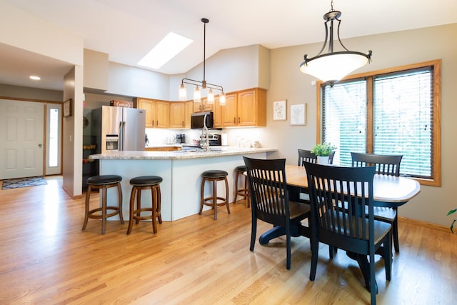 1941 230th St, Saint Croix Falls, WI 54024 - dining area featuring a skylight, light wood-type flooring, high vaulted ceiling, and baseboards