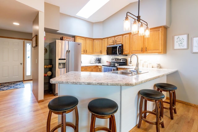 1941 230th St, Saint Croix Falls, WI 54024 - kitchen featuring appliances with stainless steel finishes, a sink, a peninsula, light wood-style flooring, and a breakfast bar area