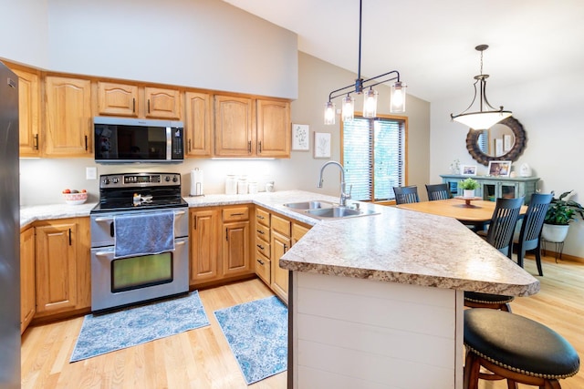 1941 230th St, Saint Croix Falls, WI 54024 - kitchen with stainless steel appliances, a sink, a peninsula, light wood-style floors, and a breakfast bar area