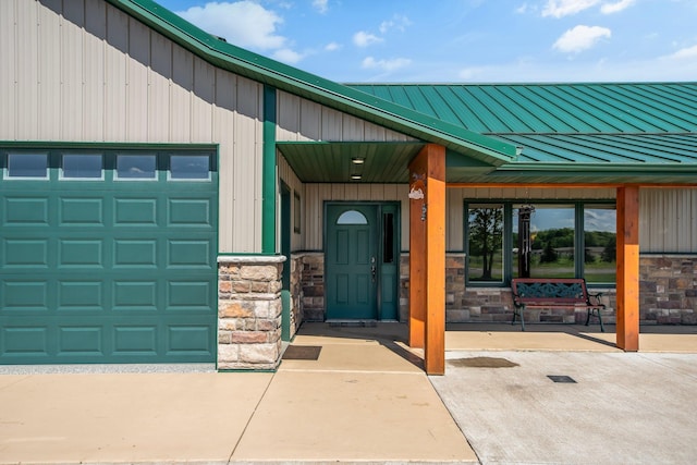 10080 550th St, Rock Creek, MN 55069 - view of exterior entry with stone siding, a garage, a standing seam roof, board and batten siding, and metal roof