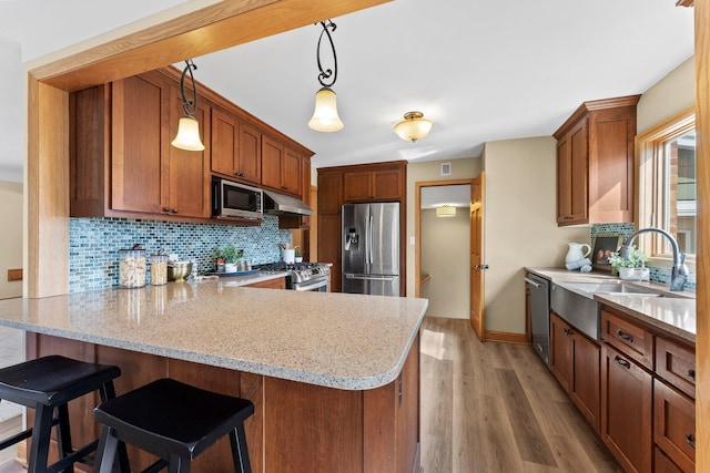 2701 Princeton Ave, Saint Louis Park, MN 55416 - kitchen featuring stainless steel appliances, a peninsula, a sink, tasteful backsplash, and brown cabinets