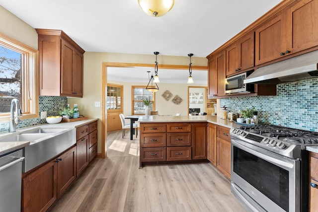 2701 Princeton Ave, Saint Louis Park, MN 55416 - kitchen with stainless steel appliances, a sink, a peninsula, under cabinet range hood, and light wood-type flooring
