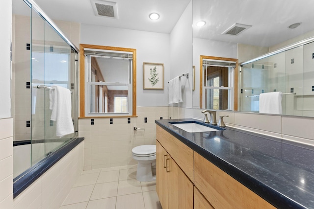 2701 Princeton Ave, Saint Louis Park, MN 55416 - bathroom with tile patterned flooring, toilet, vanity, tile walls, and a wainscoted wall