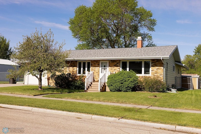 806 E St, Bottineau, ND 58318 - single story home featuring a front yard, a chimney, an attached garage, brick siding, and roof with shingles