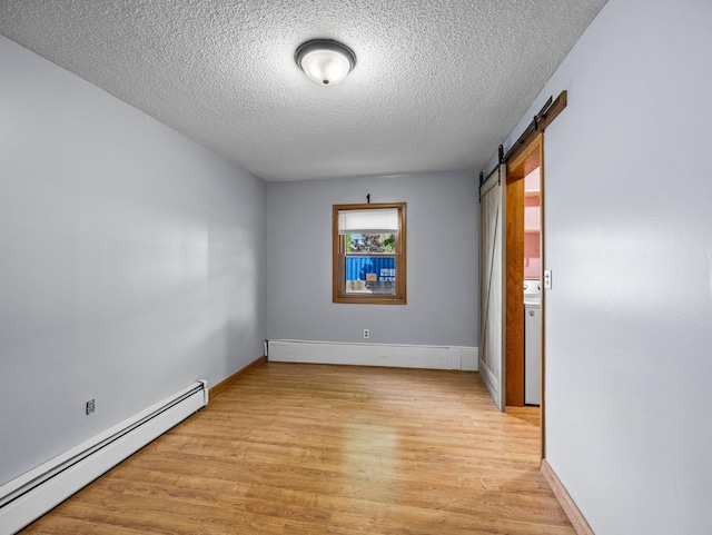 5252 5th St NE, Columbia Heights, MN 55421 - empty room with a baseboard radiator, light wood-style flooring, a textured ceiling, and a barn door