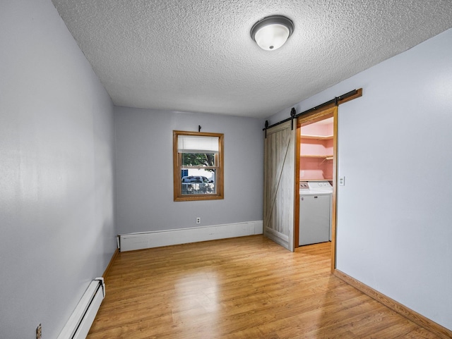 5252 5th St NE, Columbia Heights, MN 55421 - unfurnished room with washer / dryer, a barn door, a baseboard heating unit, a textured ceiling, and light wood-type flooring