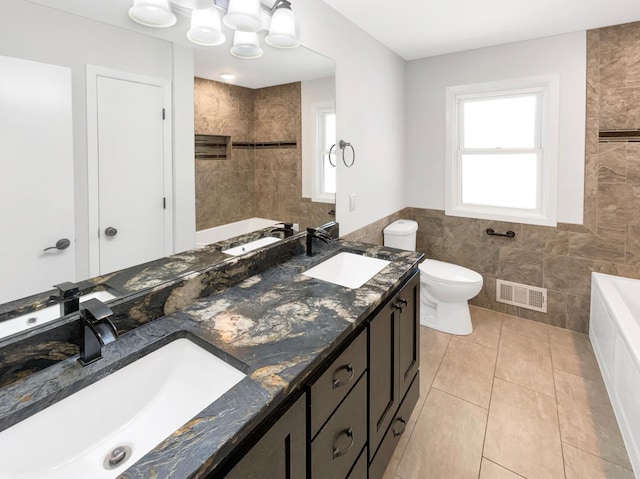 5617 220th St N, Forest Lake, MN 55025 - bathroom featuring tile walls, a bath, toilet, double vanity, and tile patterned flooring