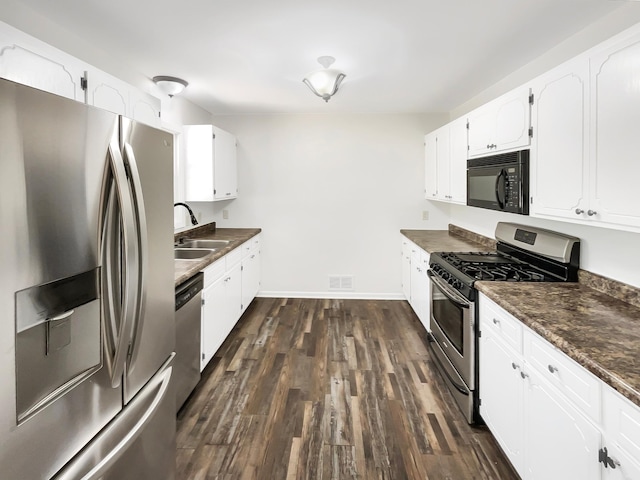 5617 220th St N, Forest Lake, MN 55025 - kitchen with appliances with stainless steel finishes, dark countertops, a sink, white cabinets, and dark wood finished floors
