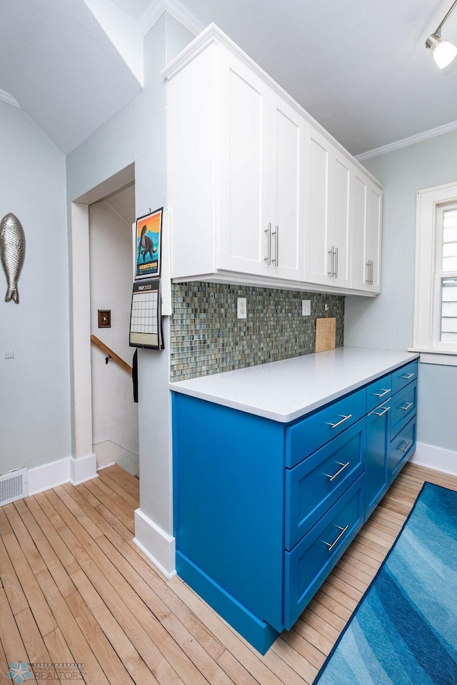 1328 6th St S, Fargo, ND 58103 - kitchen featuring blue cabinets, light wood-style flooring, tasteful backsplash, white cabinets, and crown molding